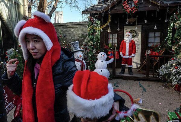 Женщина и ребенок в праздничных шляпах на рождественской ярмарке во французском стиле в Пекине, Китай. 