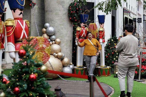 Посетители фотографируются на фоне праздничных рождественских украшений в торговом центре Paris Van Java в Бандунге, Западная Ява, Индонезия. 