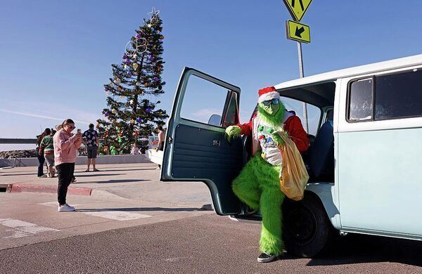 Мужчина в костюме Гринча перед началом рождественского празднования на Оушен-Бич в Сан-Диего, Калифорния.