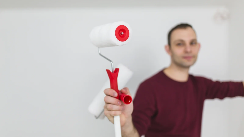 Мужчина с валиком для идеальной покраски потолока