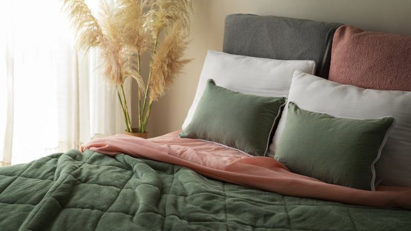 Подушки и одеяло лежат на кровати и требуют правильной стирки