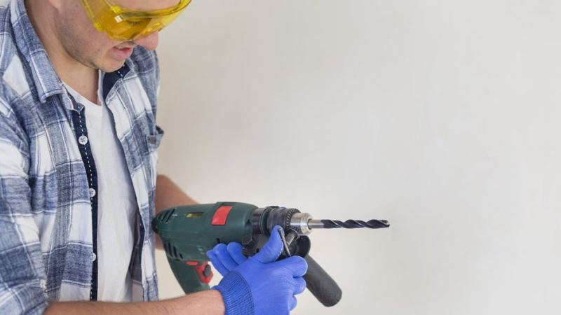 Рабочий собирается сверлить керамическую плитку