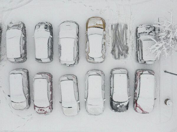 Аэрофотоснимок припаркованных автомобилей, покрытых снегом, в Мысленице, Польша