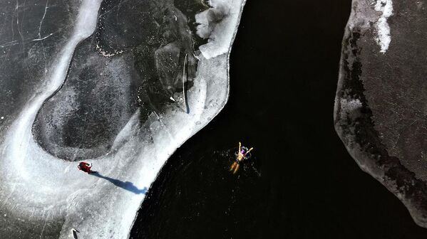 На аэрофотоснимке, сделанном в Шэньяне, провинция Ляонин, Китай, любитель зимнего плавания купается в ледяных водах реки, несмотря на сильный холод.