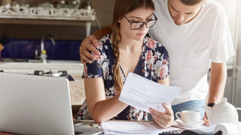 Женщина и мужчина изучают квитанцию за ЖКУ, проверяя наличие переплаты за теплоснабжение